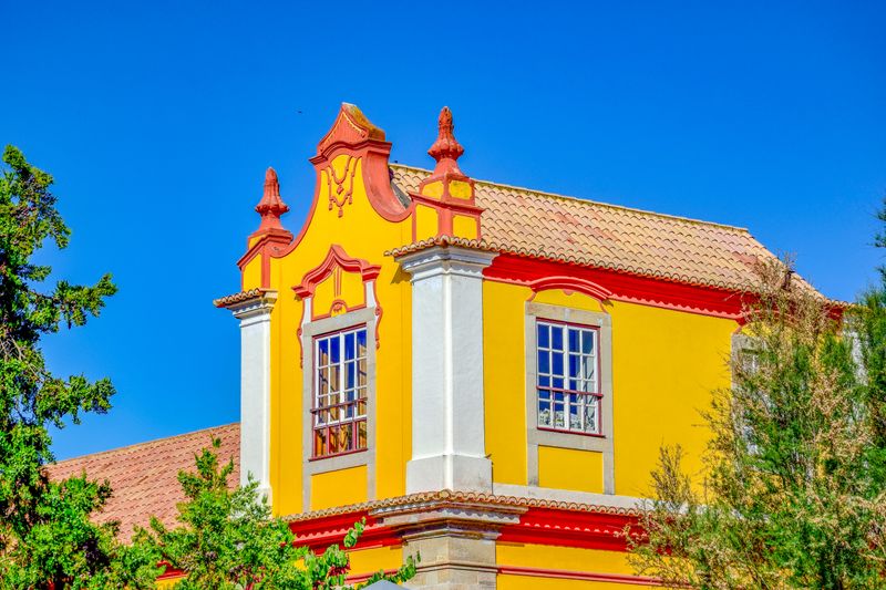 Vibrant yellow historic building facade in Tavira, Portugal, under a clear blue sky.
