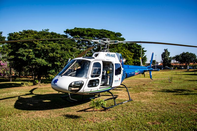 A medical helicopter on a grass field in Londrina, Brazil, under clear skies.