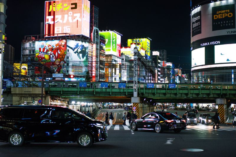Dynamic cityscape of Shinjuku, Tokyo at night with bright neon lights and bustling streets.