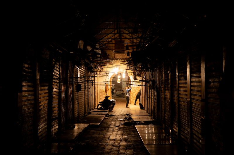 A dimly lit alleyway in Marrakech Medina at night, showcasing local life and architecture.
