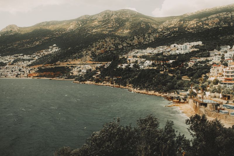 A picturesque view of a Mediterranean coastal town nestled against a mountain backdrop.