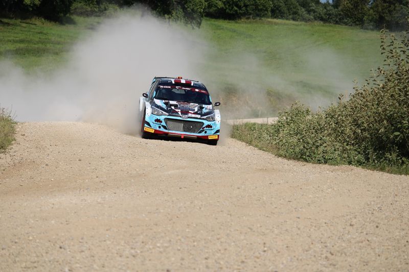 Dynamic rally car speeding on a gravel road creating dust clouds, in Cesvaine, Latvia.