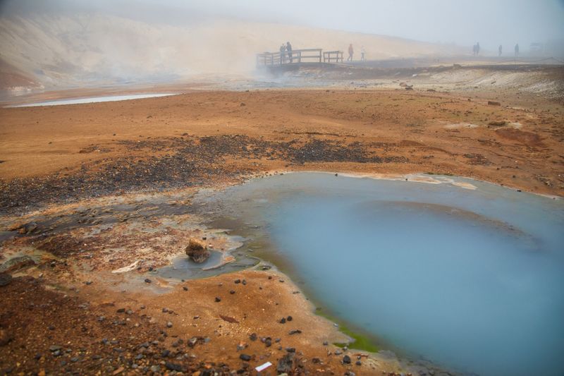 Explore a misty Icelandic geothermal area with vibrant colors and dramatic scenery.