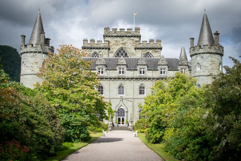 Stunning view of Inveraray Castle showcasing its grand architecture surrounded by lush gardens under a dramatic sky.