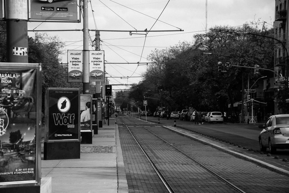 Black and white view of a tram stop in Mendoza, Argentina, capturing urban life.