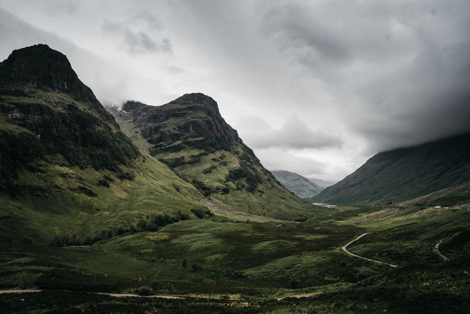 Stunning view of Glencoe Valley showcasing rugged mountains and lush greenery under an overcast sky.