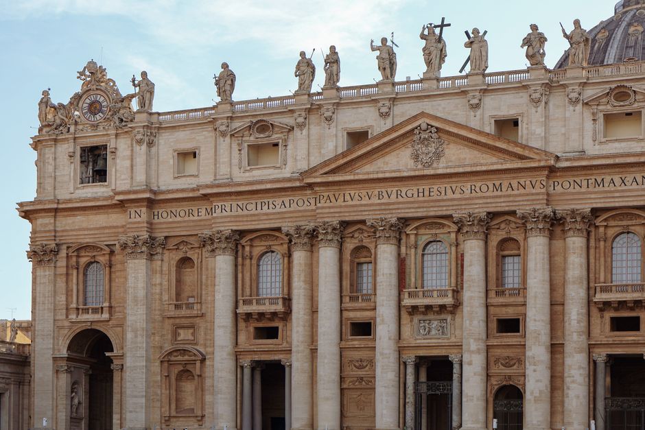 Detailed view of St. Peter's Basilica facade with statues and columns in Vatican City.