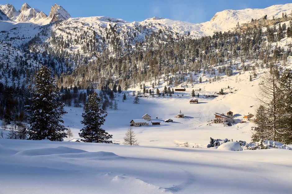 Breathtaking winter scene of the snowy Alps in the Dolomites, Italy, with quaint villages and forests.