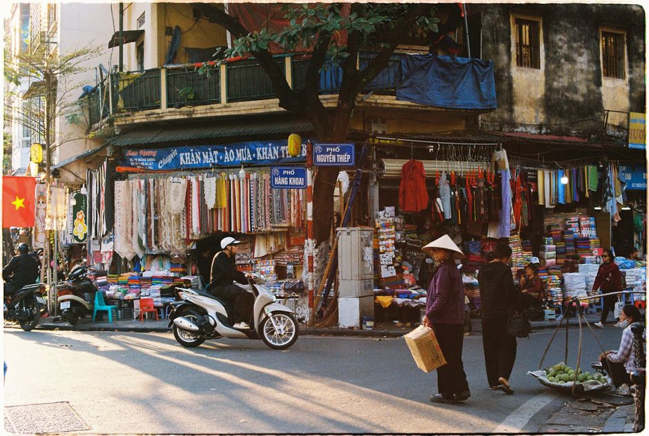 Vibrant street market in Hanoi, Vietnam with people and colorful fabrics.