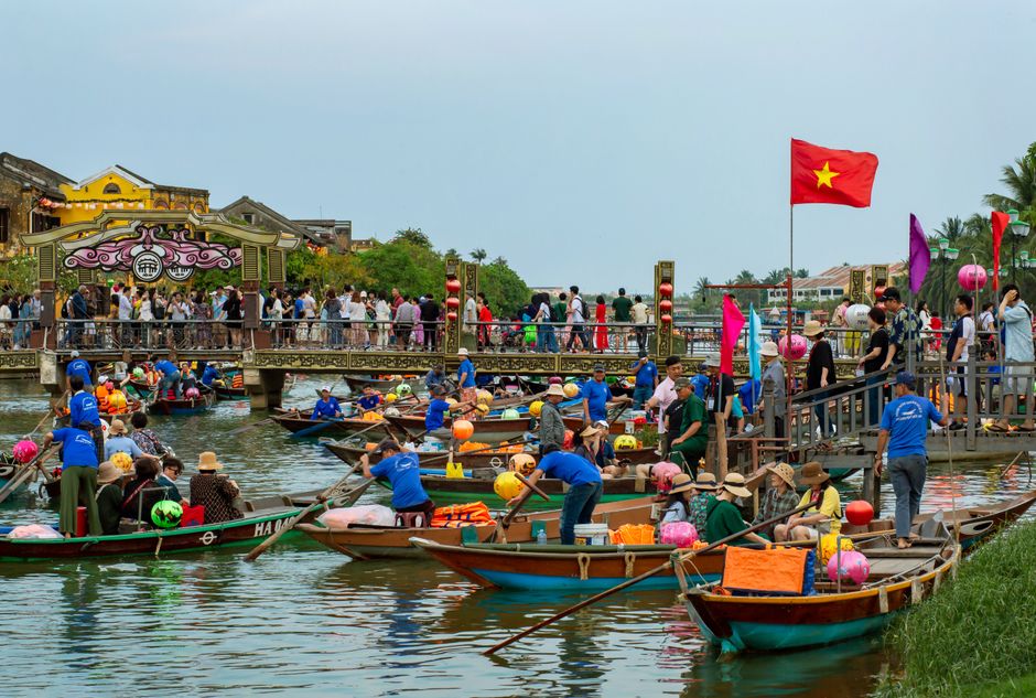 Colorful boats and crowds on the river in Hoi An, Vietnam showcasing cultural vibrancy.