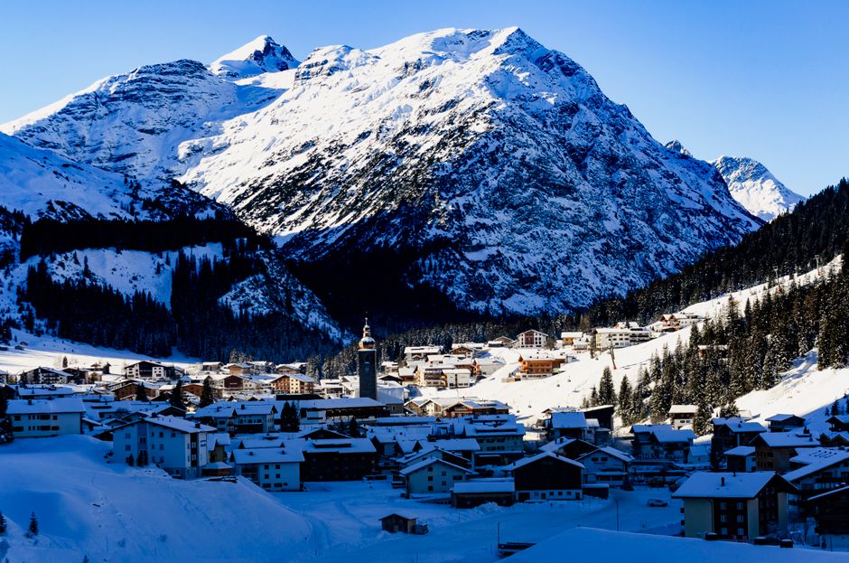 Scenic winter view of snow-covered Lech village with majestic Alps backdrop.