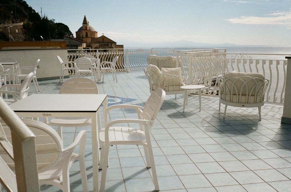 Elegant white patio furniture on a terrace overlooking the Amalfi Coast with a stunning sea view.